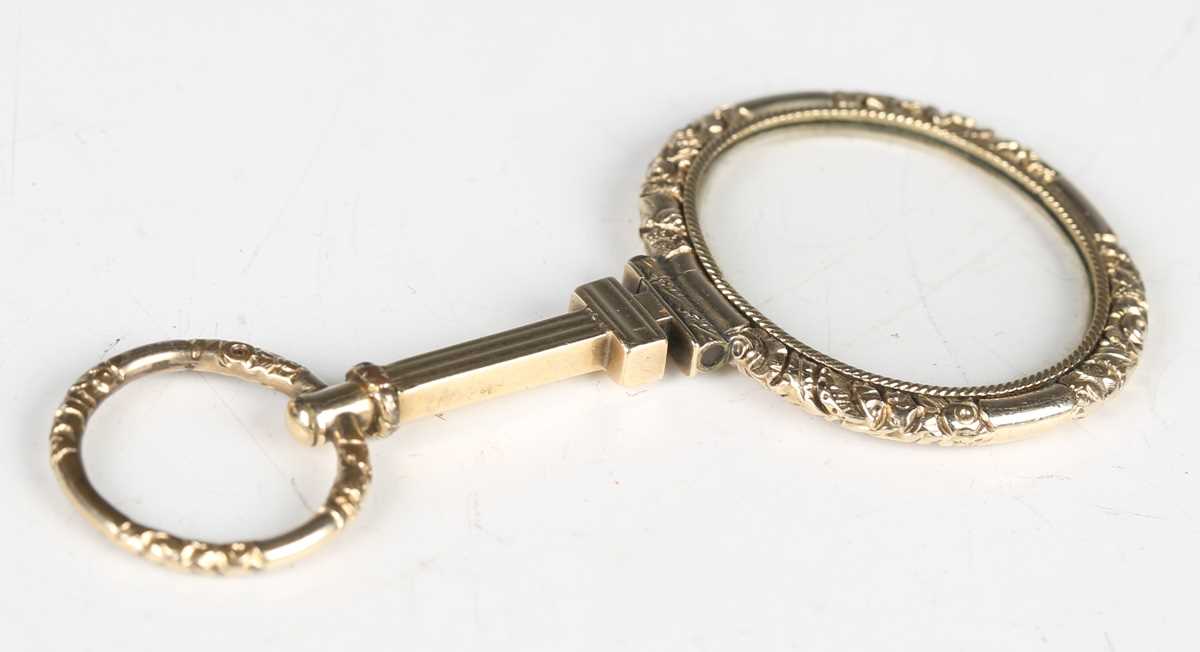 A mid-19th century gold framed magnifying lens, finely chased with foliage, length 8cm.