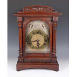 An early 20th century German oak mantel clock with eight day movement chiming on gongs, the silvered