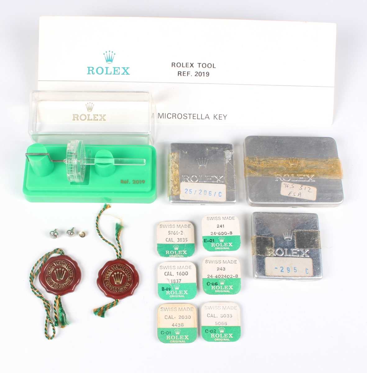 A collection of assorted wristwatch parts, including Rolex and Piaget aluminium small parts cases, a