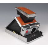 A Polaroid SX-70 land camera with tan leather cover, length 17.7cm.