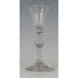 A balustroid gin or cordial glass, circa 1730-40, the rounded funnel bowl with teared solid base,
