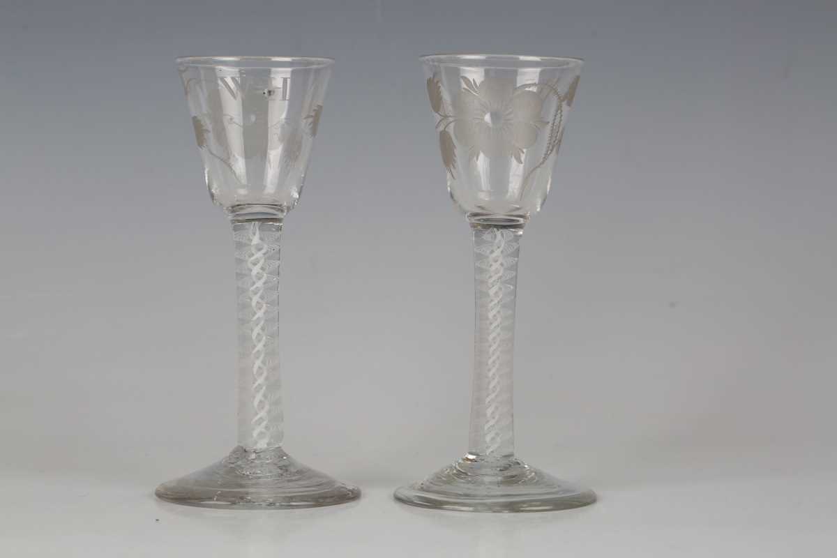 A pair of engraved double series opaque twist stem wine glasses, circa 1765, the rounded funnel