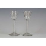 A pair of engraved double series opaque twist stem wine glasses, circa 1765, the rounded funnel