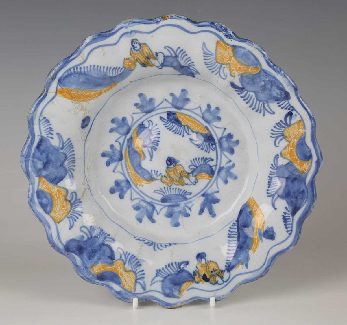 A Dutch Delft lobed buckle dish, circa 1700, painted in blue and yellow with Chinese figures to