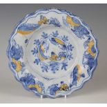 A Dutch Delft lobed buckle dish, circa 1700, painted in blue and yellow with Chinese figures to