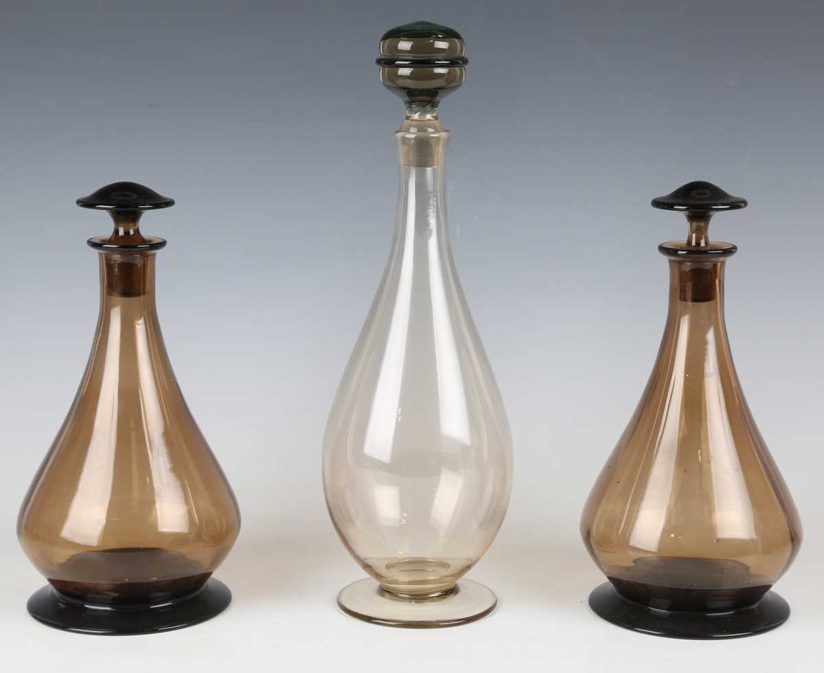 A pair of glass decanters and stoppers, probably Scandinavian, the pear shaped amber glass bodies