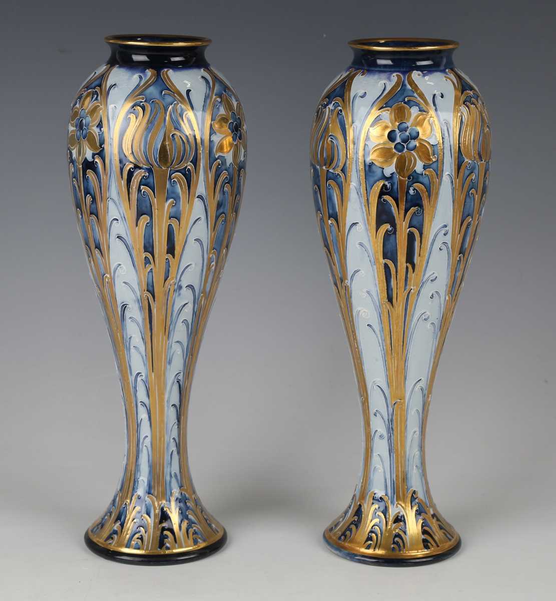 A pair of Macintyre Moorcroft blue and gold Florian design vases, early 20th century, with tall
