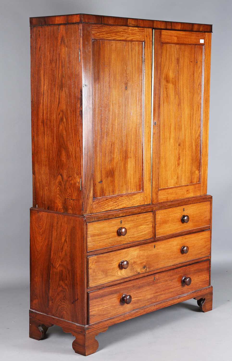 An early 19th century Colonial padauk linen press, the two panelled doors above four drawers, height