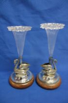 A pair of silver plated epergnes with swan decorated bases supporting clear glass trumpet spills