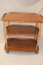 A 1960s Ercol pale elm three tier tea trolley on tapered supports