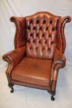 A good quality traditional wing easy chair upholstered in brown buttoned leather on cabriole legs
