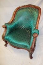 A reproduction French carved easy chair upholstered in green fabric on scroll legs