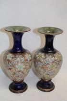 A pair of Royal Doulton pottery baluster-shaped vases with floral decoration on blue and gold