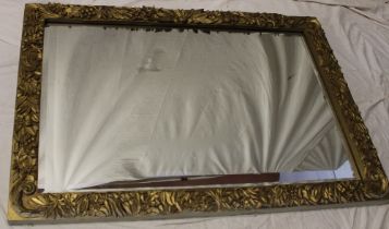A rectangular wall mirror in ornate floral and leaf decorated wood frame,