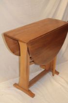 A 1970's Ercol light elm oval drop-leaf dining table on standard supports,