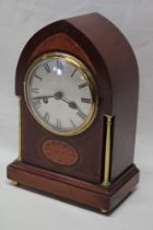 An Edwardian mantel clock with silvered circular dial in inlaid mahogany and brass mounted gothic