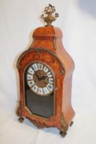 An ornate French mantel clock with brass circular dial and individual porcelain numerals in walnut
