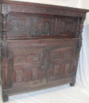 A 17th Century carved oak court cupboard with shelves enclosed by two heavily carved and decorated