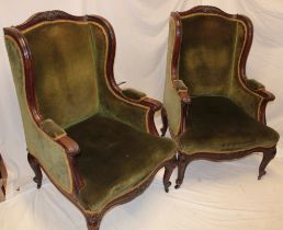 A pair of Victorian carved oak wing easy chairs upholstered in green fabric on scroll-shaped legs