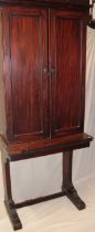 An early 19th century mahogany pier cabinet and stand with shelves enclosed by two panelled doors