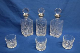 Three matching cut-glass decanters with silver-plated necks and faceted stoppers and three