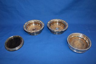A pair of 19th century Sheffield plate circular bottle coasters with polished wood bases and raised