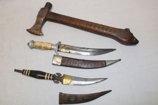 An old Tomahawk-style axe with carved wood handle and two various Eastern daggers with scabbards