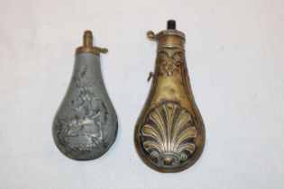 A 19th century brass powder flask with raised decoration and a 19th century zinc powder flask with