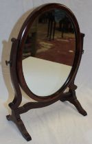 An small Edwardian mahogany oval swing toilet mirror on scroll supports,