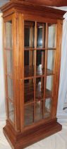 A reproduction mahogany full length display cabinet with mirror back and shelves enclosed by a