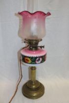 A late Victorian brass oil lamp with pink tinted opaque glass reservoir and cranberry tinted glass