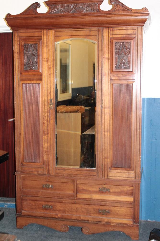 A Victorian walnut wardrobe with hanging compartment enclosed by a central mirror panel door above