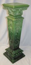 A large green glazed pottery square tapered jardiniere stand decorated in relief with classical