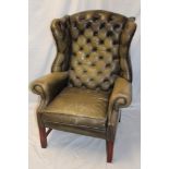 A mahogany traditional wing easy chair upholstered in green buttoned leather