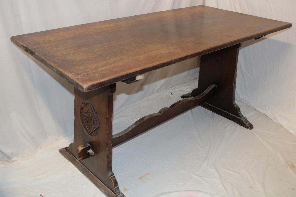 A rustic carved oak rectangular refectory dining table, the ends with floral emblems,