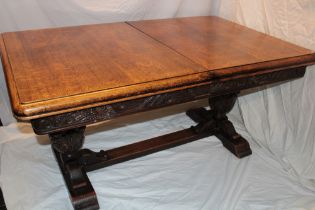 A 1930's oak rectangular draw-leaf refectory-style table with decorated frieze on carved supports