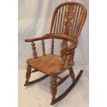 An old polished elm and beech Windsor-style rocking chair with splat and spindle back and shaped