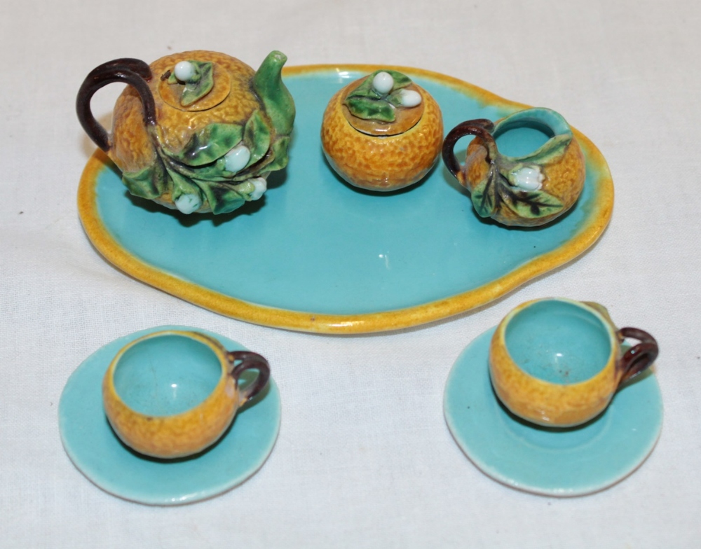 An unusual majolica glazed miniature tea set with raised floral decoration comprising a tea pot,