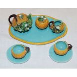 An unusual majolica glazed miniature tea set with raised floral decoration comprising a tea pot,