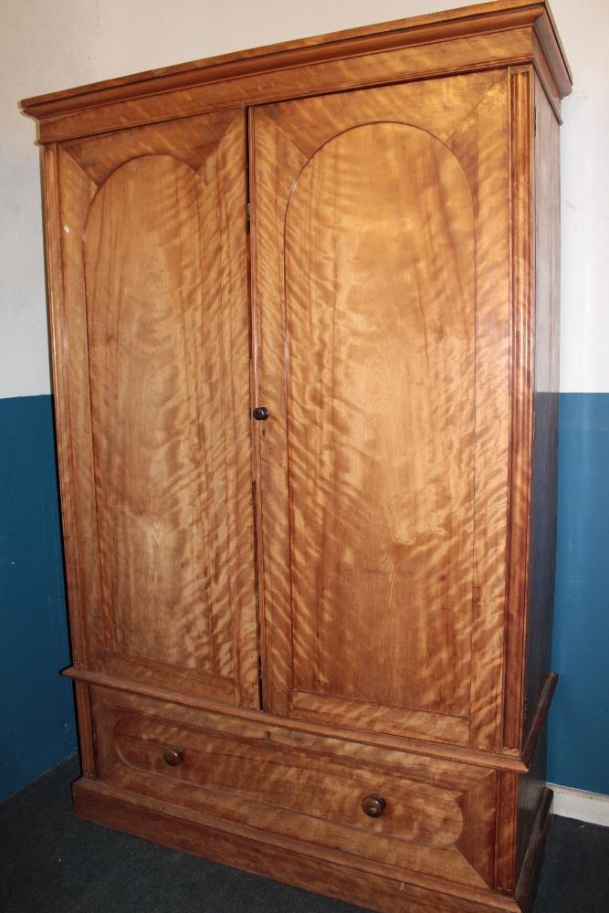 A 19th century satinwood gents wardrobe with sliding trays enclosed by two arched panelled doors