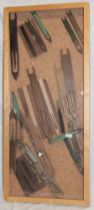 A glazed display case containing a collection of fisherman's net mending tools including some