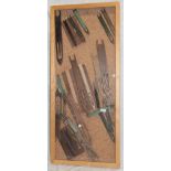 A glazed display case containing a collection of fisherman's net mending tools including some