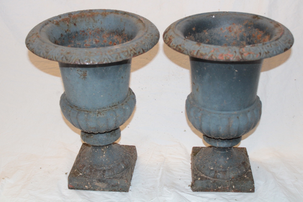 A pair of small cast iron classical-shaped garden urns with fluted columns and square bases,