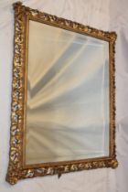 A bevelled rectangular wall mirror in gilt pierced and scroll decorated frame,