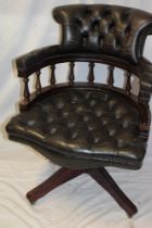 A reproduction mahogany swivel office chair upholstered in green buttoned leather