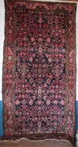 An Eastern hand knotted wool rug with floral decoration on red and blue ground,