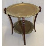 An Eastern occasional table with twin brass tray tops with decorated edges on carved wood folding