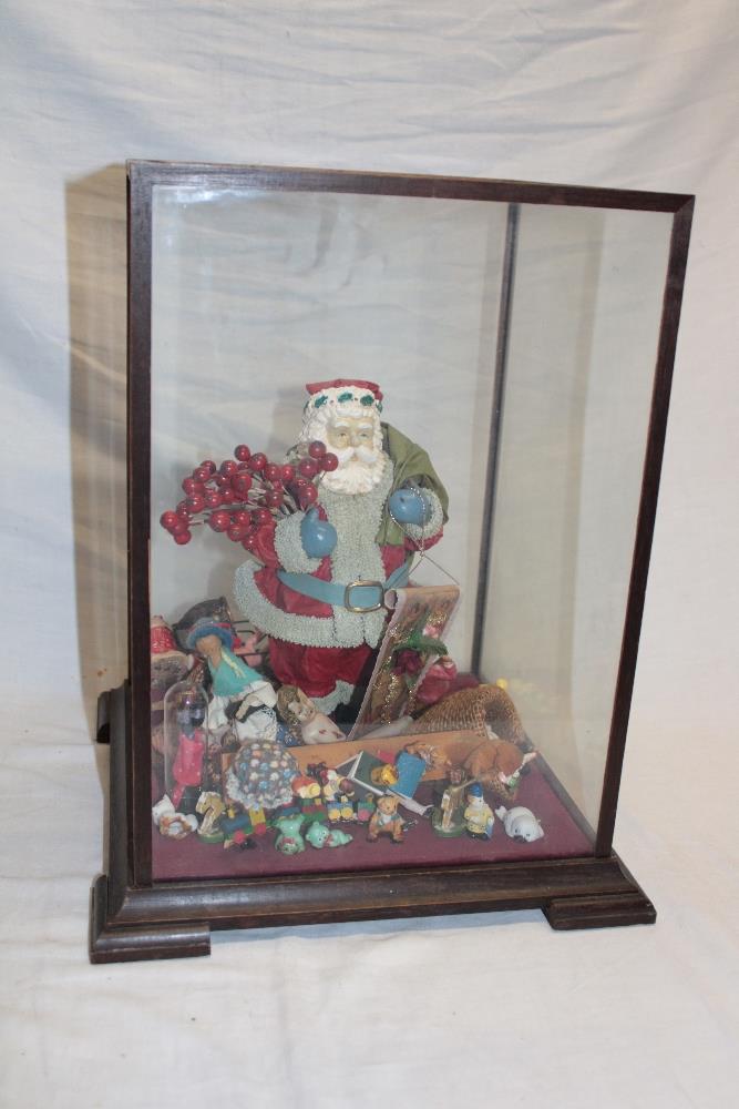 A modern Father Christmas display with other decorations within a mahogany glazed display case,