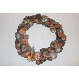 A Cornish art metal circular wall plaque in the form of copper and steel leaves,