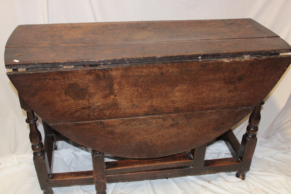 A Charles II and later oak oval drop leaf dining table on baluster turned supports,